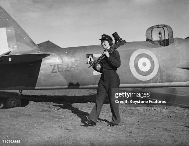 Member of the Women's Auxiliary Air Force carrying an aircraft machine gun at No 1 Air Gunners School, RAF Pembrey, Carmarthenshire, Wales, 1st April...