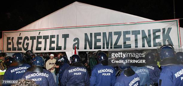 Hungarian riot police officers stand guard in front of an election tent of the coalition governor of Socialist party, the Free Democrats Alliance, at...