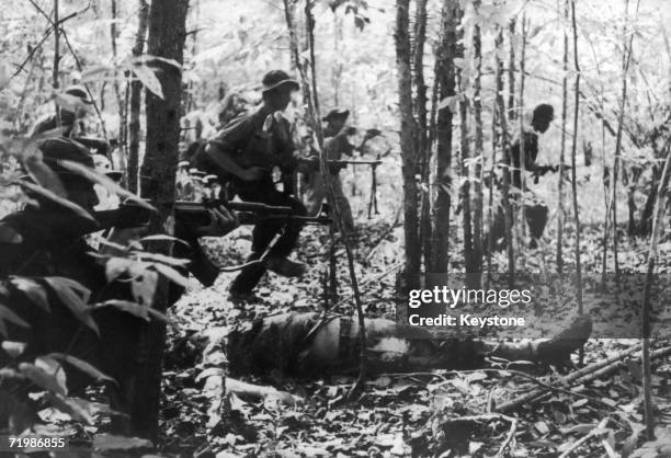 Viet Cong detachment going into battle during the Vietnam War, January 1967. In the foreground is the body of a dead American soldier.