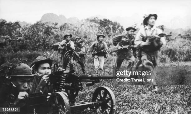 Viet Cong soldiers moving forward under covering fire from a heavy machine gun during the Vietnam War, circa 1968.