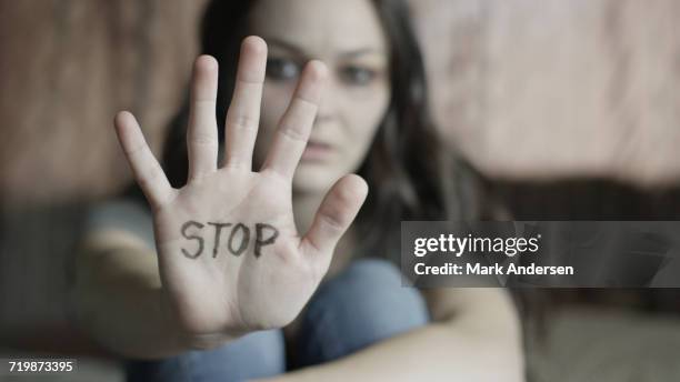 close up of woman holding out hand with stop writing on bed - domestic violence stock pictures, royalty-free photos & images