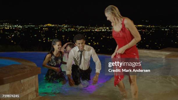 high angle selective focus view of laughing friends partying and playing in hot tub on balcony overlooking scenic view of landscape - hot tub party stock pictures, royalty-free photos & images
