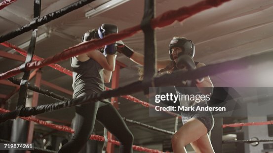 Low angle view of female boxers punching and fighting in boxing ring during match Low angle view of female boxers punching and fighting in boxing ring during match