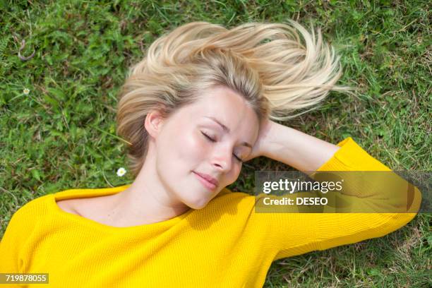 portrait of a pretty blond woman lying down in the park with closed eyes - face eyes closed stock pictures, royalty-free photos & images