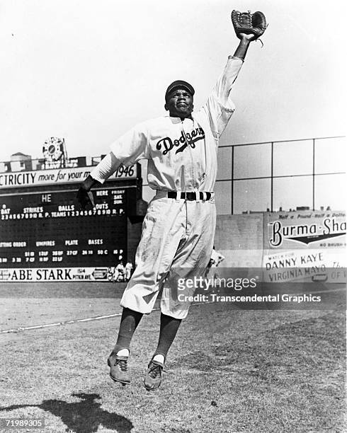 Jackie Robinson, first baseman for the Brooklyn Dodgers, leaps for a throw during warm ups before a game in 1947 at Ebbets Field.