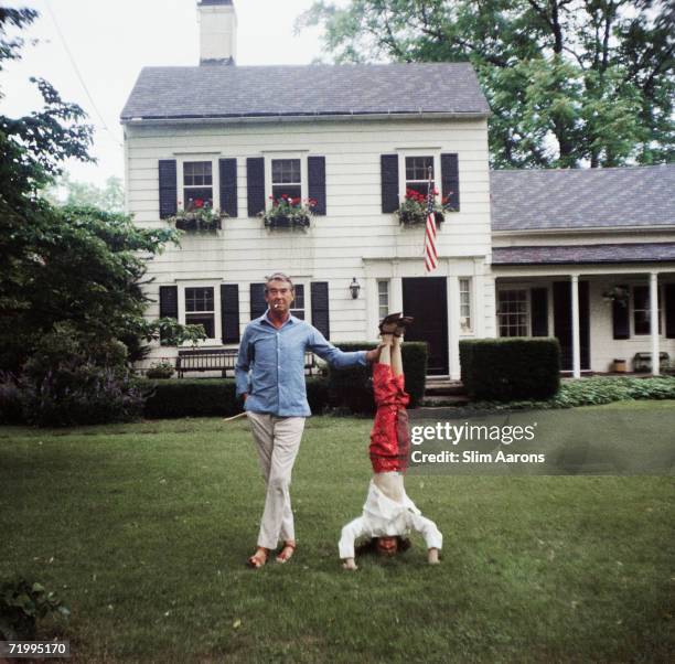 Society photographer Slim Aarons helps his daughter Mary to sustain a headstand, Bedford, New York, 4th July 1970.