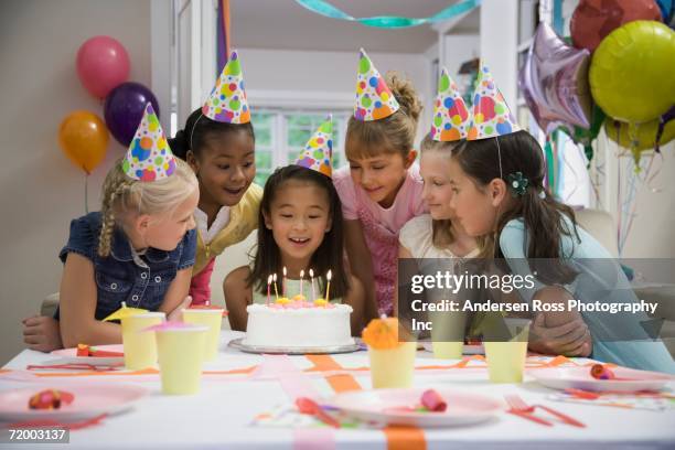 asian girl blowing out candles at birthday party - kindergeburtstag stock-fotos und bilder