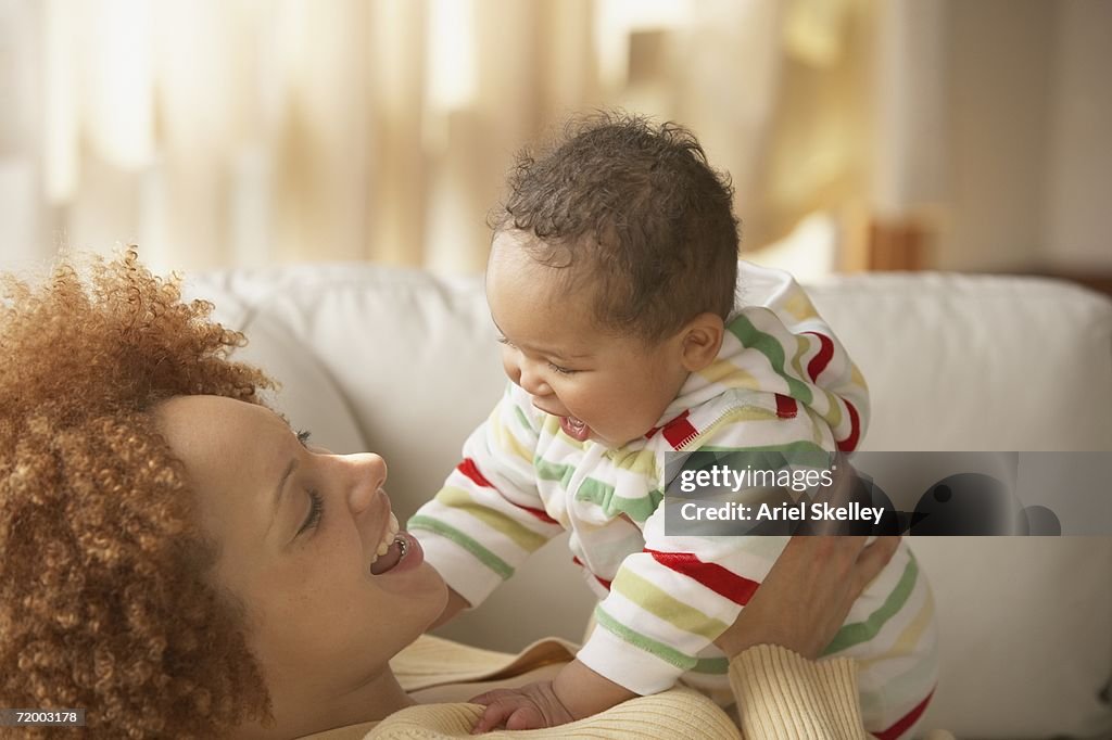 African mother and baby smiling at each other on sofa