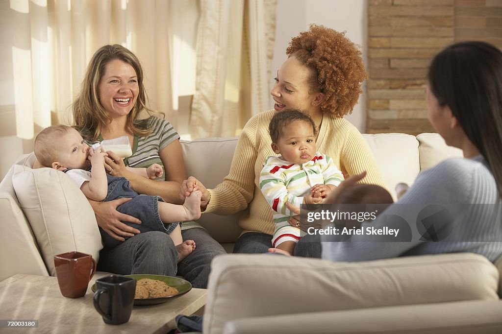 Three young mothers with babies on sofa