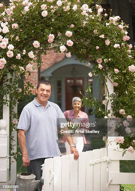 senior hispanic couple under flowered archway with watering can - white rose garden stock pictures, royalty-free photos & images