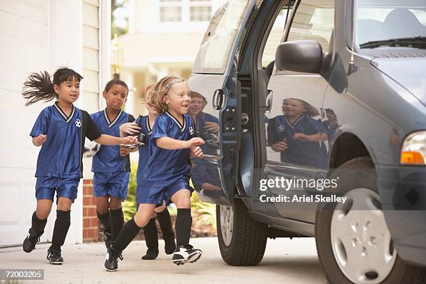 children in soccer outfits getting into car - motorized sport photos et images de collection