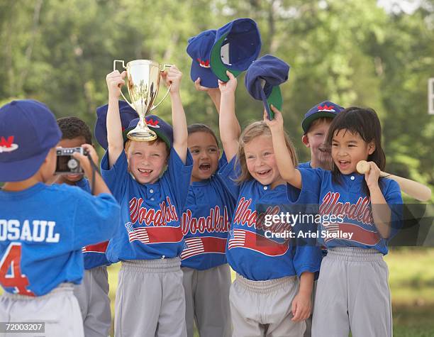 children in baseball outfits cheering with trophy - girl baseball cap stock pictures, royalty-free photos & images