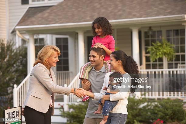 hispanic family shaking hands with real estate agent in front of house - house sold imagens e fotografias de stock