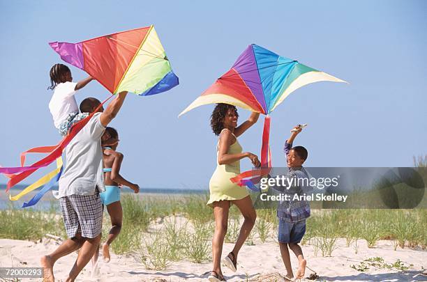 african family flying kites on beach - people flying kites stockfoto's en -beelden