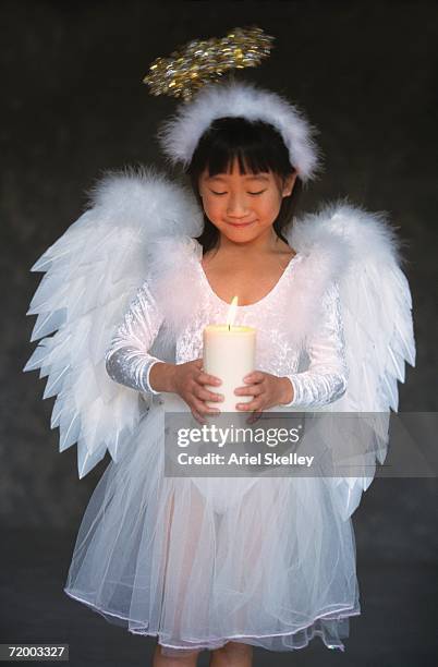 asian girl in angel costume holding candle - kerstkind stockfoto's en -beelden