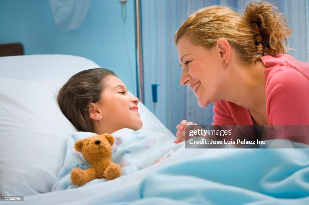 Mother smiling at daughter in hospital bed