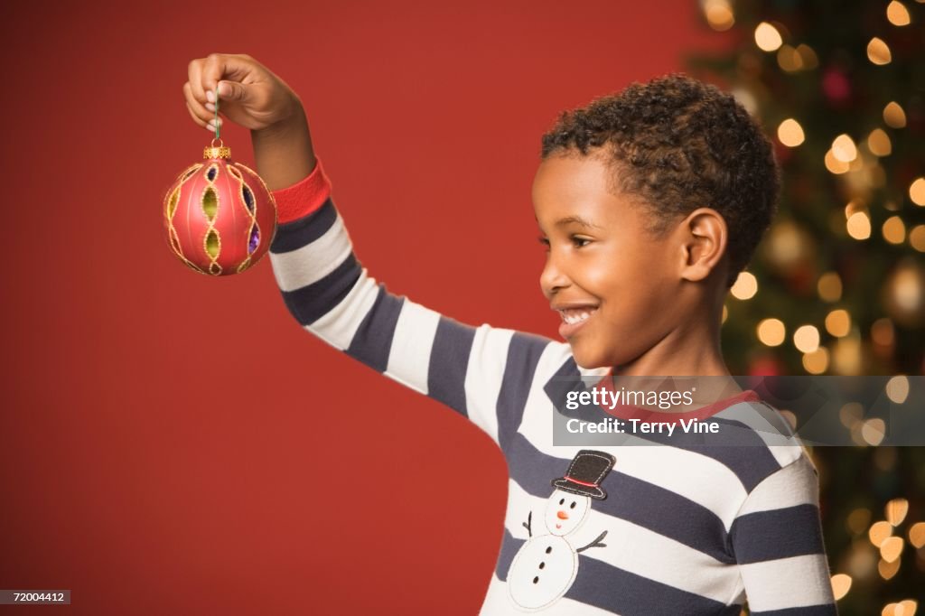 African boy smiling and holding Christmas ornament