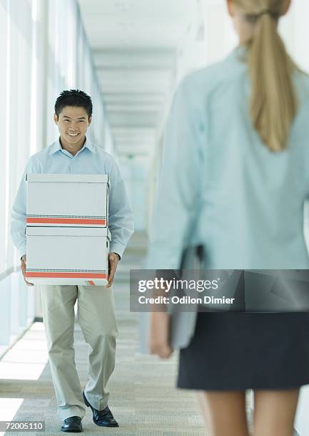 man carrying boxes in hallway, smiling at female colleague - blouse back stock pictures, royalty-free photos & images