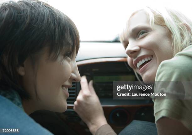 two female friends in car, one tuning radio - car tuning stock pictures, royalty-free photos & images