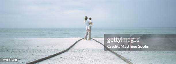 mother and child standing at end of path on beach - the bigger picture stock pictures, royalty-free photos & images