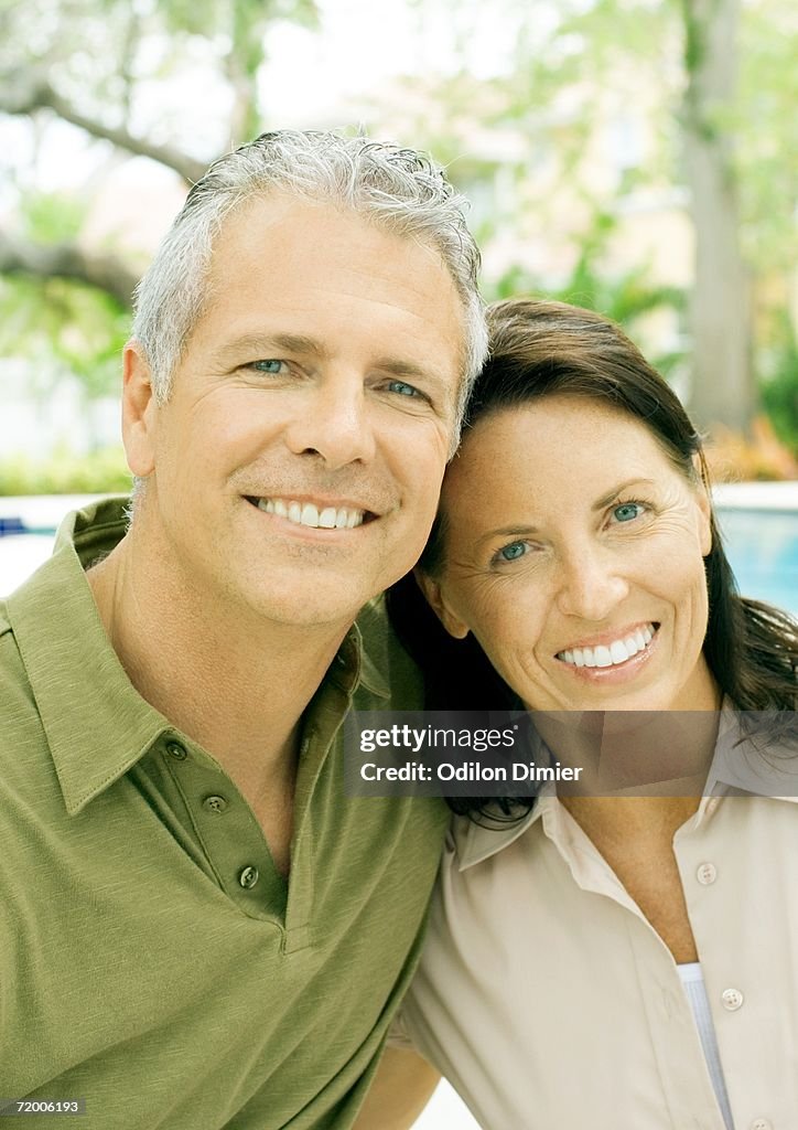 Mature couple smiling, portrait, pool in background