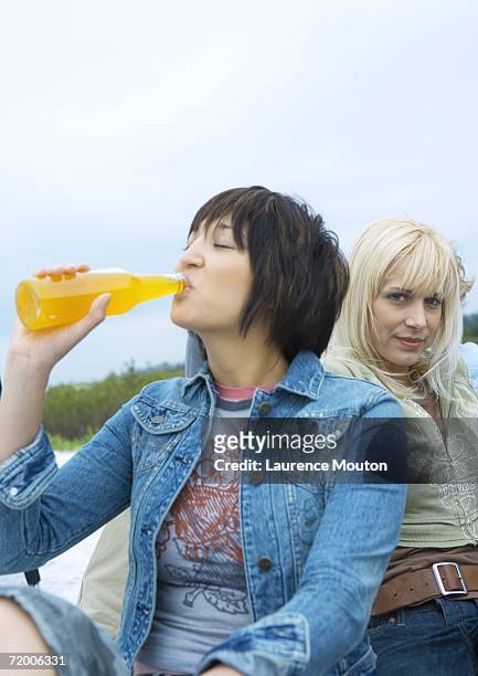 young woman drinking orange soda - asian female friends drinking soda outdoor stockfoto's en -beelden