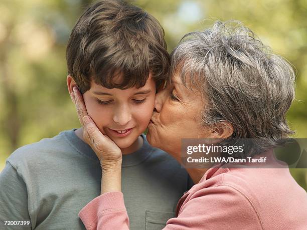 hispanic grandmother kissing grandson on cheek - friends kissing cheeks fotografías e imágenes de stock