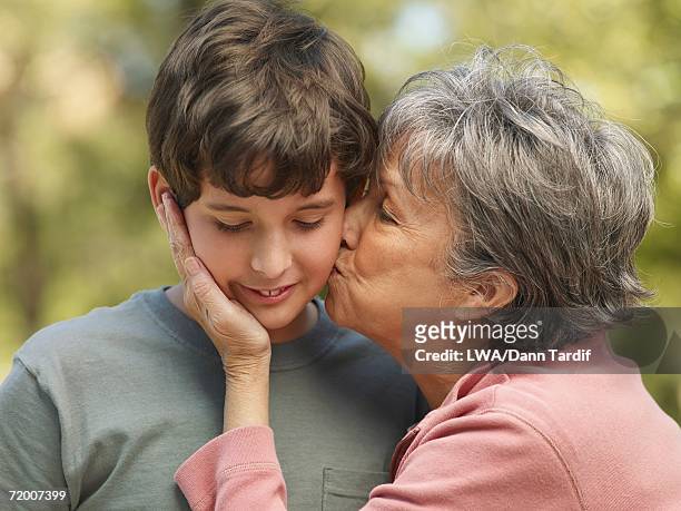 hispanic grandmother kissing grandson on cheek - cheek kiss stock pictures, royalty-free photos & images