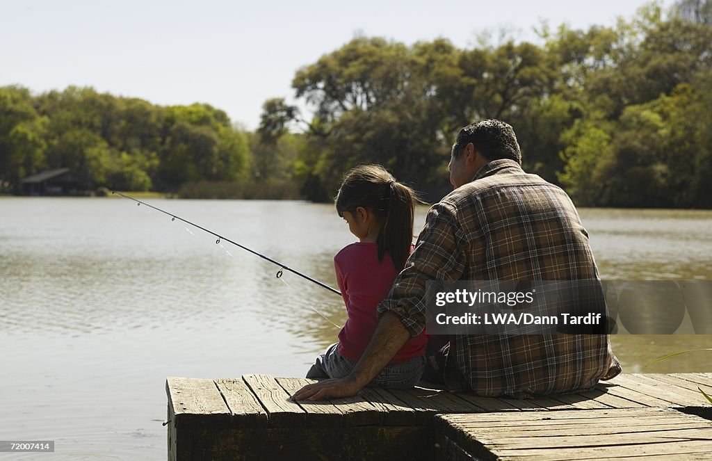 Father and daughter fishing on dock