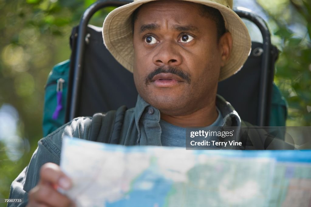 African man with map and backpack in woods