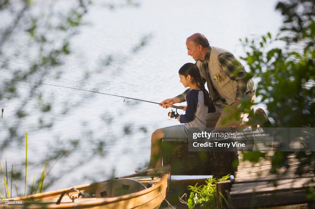 Grandfather and granddaughter fishing on dock