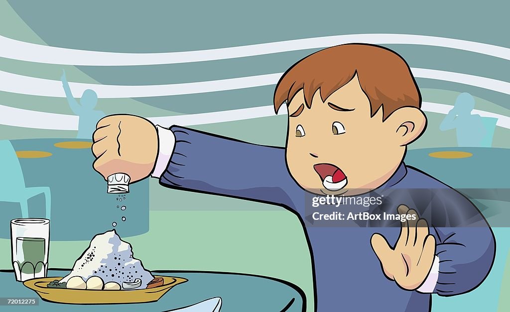 Close-up of a boy pouring salt on food
