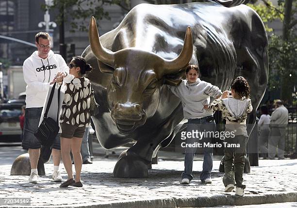 People take photos of the famous bull statue near the New York Stock Exchange September 28, 2006 in New York City. The Dow Jones Industrial Average...
