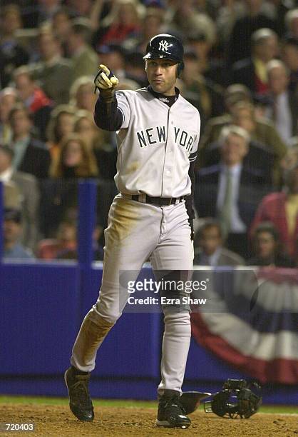 Derek Jeter of the New York Yankees motions to teammate David Justice after scoring on a Justice RBI triple in the third inning against the New York...