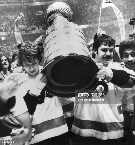 Canadian hockey players Bobby Clarke and Bernie Parent of the Philadelphia Flyers carry the Stanley Cup as they celebrate their series-winning...