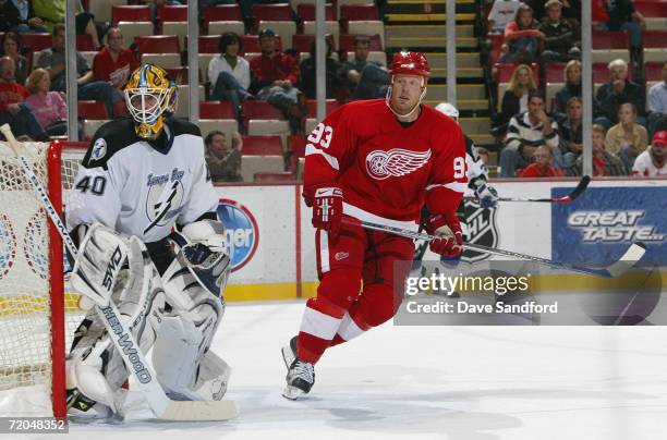 Goaltender Johan Holmqvist of the Tampa Bay Lightning defends his net as Johan Franzen of the Detroit Red Wings skates past the crease area during...