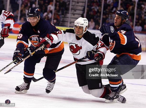 Scott Gomez of the New Jersey Devils reaches for the puck between Alexei Yashin and Chris Campoli of the New York Islanders during their NHL...
