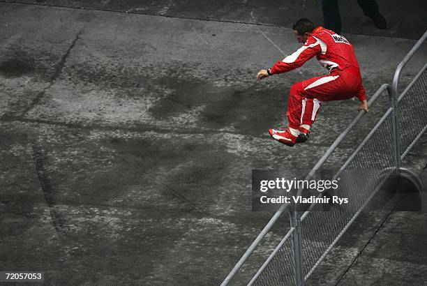 Michael Schumacher of Germany and Ferrari jumps over a fence to celebrate with his team after winning the Chinese Formula One Grand Prix at the...