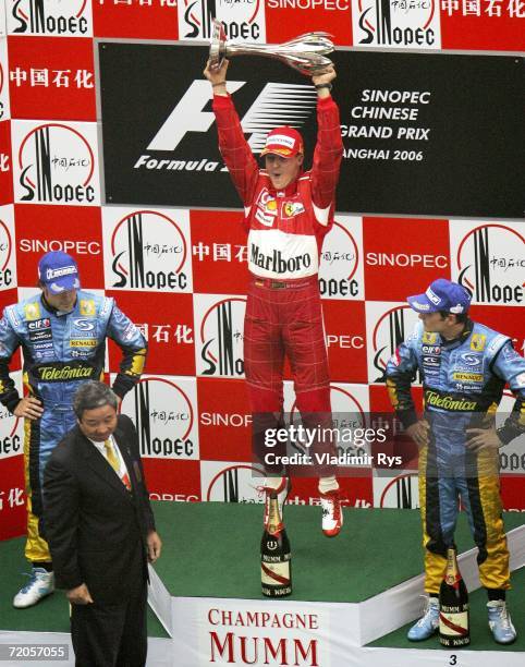 Michael Schumacher of Germany and Ferrari celebrates with the trophy as Fernando Alonso of Spain, finishing 2nd, and his team mate Giancarlo...