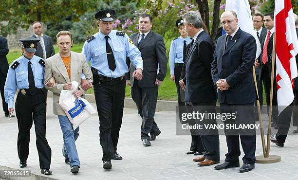 Georgian police officers escort a Russian officer accused of spying as they pass by OSCE chairman in office, Belgian Forgeign Minister Karel De Gucht...