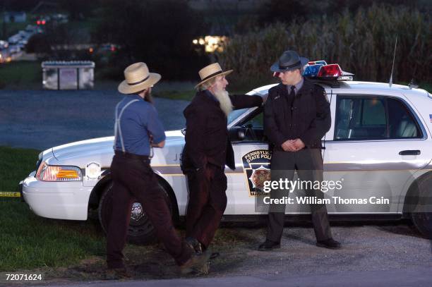 Members of the Amish community speak with a Pennsylvania State Trooper at the scene of a shooting at a one room Amish schoolhouse October 2, 2006 in...