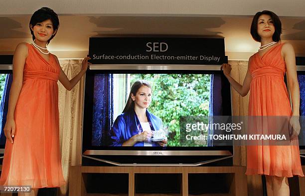 Models poses next to a new generation flat display TV, using 55-inch SED panel at the SED booth of the CEATEC, IT and Electronics exhibition in...