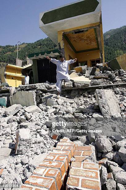 Pakistani earthquake survivor makes his way through the rubble of a house which collapsed in the 08 October 2005 earthquake in Balakot, in the North...