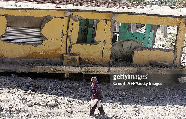 Pakistani earthquake survivor Khatija Bebi walks past a house which was damaged in the 08 October 2005 earthquake in Balakot, in the North West...