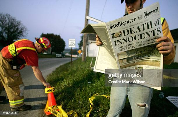 Man who did not wish to give his name reads a newspaper with the headline reading "Death of Innocents" while standing at road block near the scene of...