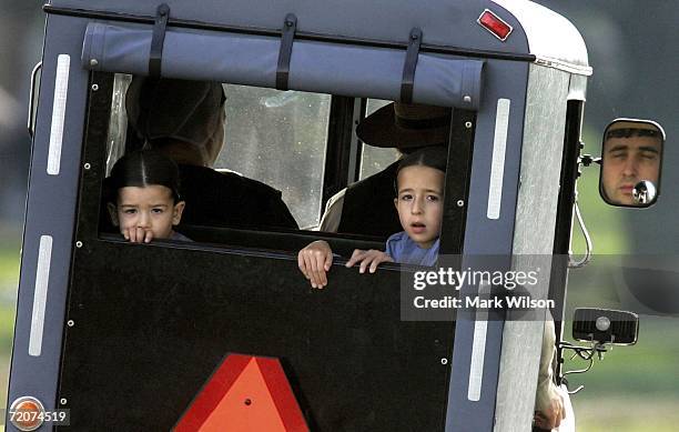 Two young Amish girls ride in the back of a horse drawn buggy near the scene of the shooting yesterday at a one room Amish schoolhouse October 3,...