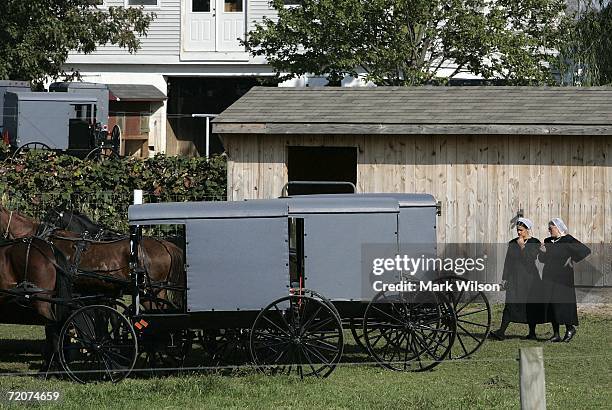 Two Amish women stand near horse drawn buggies parked at the home of one of the girls that was killed yesterday at the one room Amish schoolhouse...