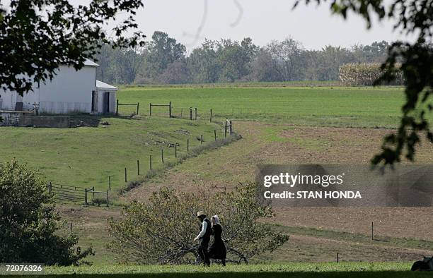 Nickel Mines, UNITED STATES: An Amish couple walk on a farm located near the one-room West Nickel Mines Amish School, 03 October 2006 in the town of...