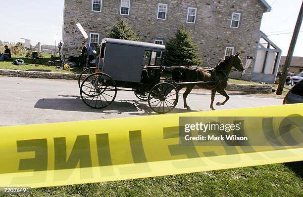 Horse drawn buggy travels past police tape near the one room Amish school house where five girls were shot and killed, October 3, 2006 in Nickel...