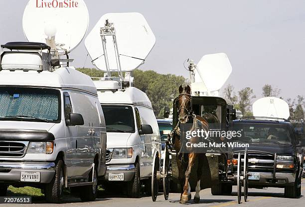 Horse drawn buggy passes a line of satellite trucks October 3, 2006 in Nickel Mines, Pennsylvania. According to officials a milk truck driver...